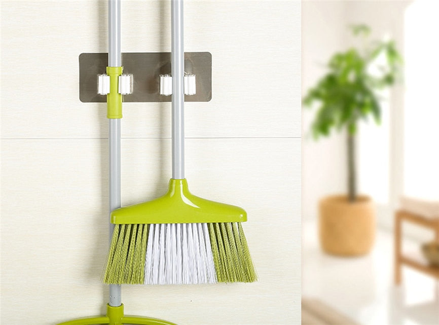 Wall-mounted cleaning tool holder securing a green broom against the wall.