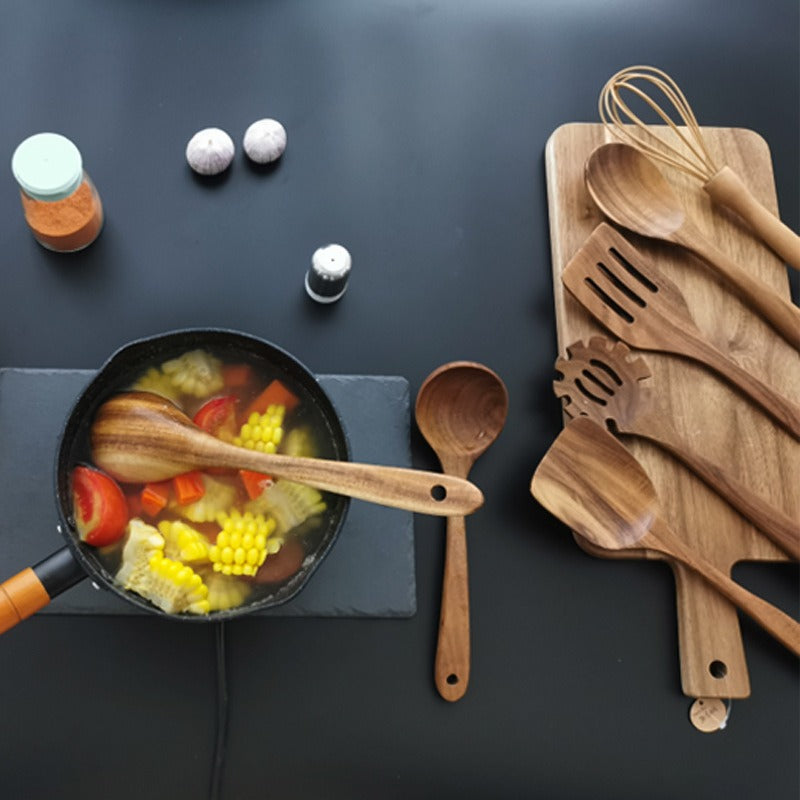 Wooden cooking utensils beside a pan of vegetable soup