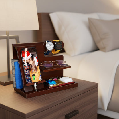 Wooden men's nightstand organizer with charging phone, two watches, glasses, wallet, cards, pens, and accessories