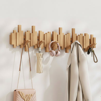 Wooden wall mounted coat rack with hooks holding bags, headphones, clothing, and accessories in an entryway